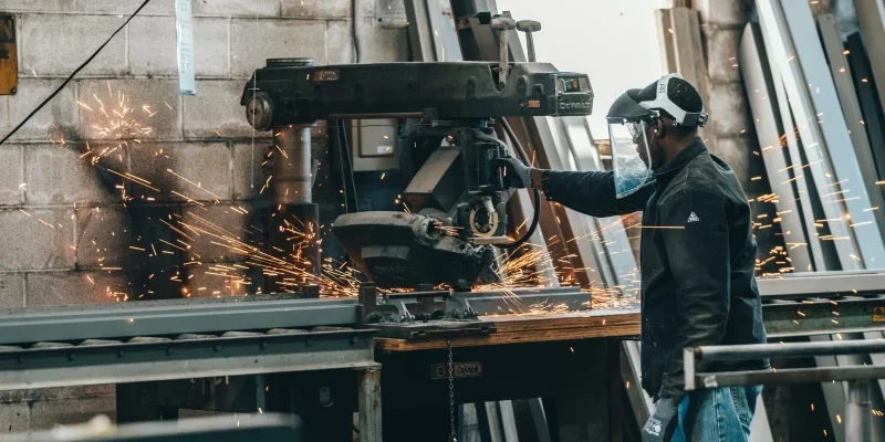 A person manipulating a machine to cut metal