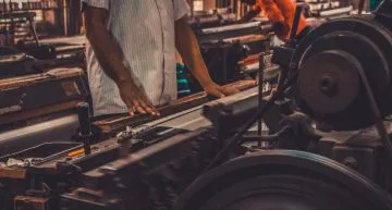 A person manipulating a machine to produce aluminum gear