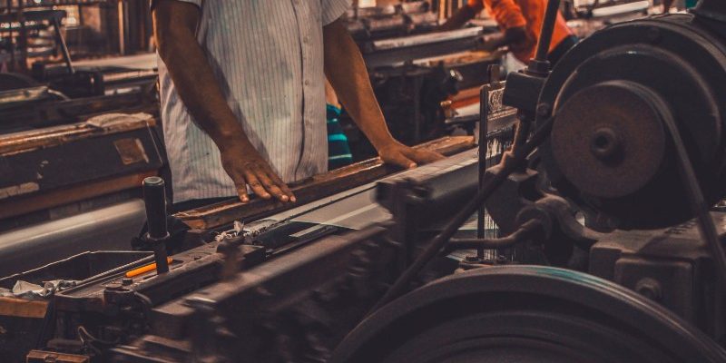 A person manipulating a machine to produce aluminum gear