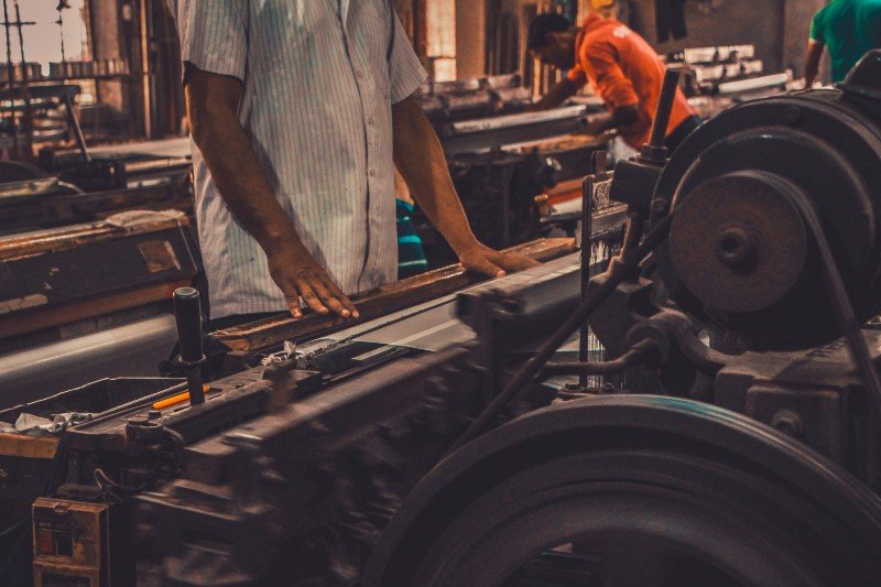 A person manipulating a machine to produce aluminum gear